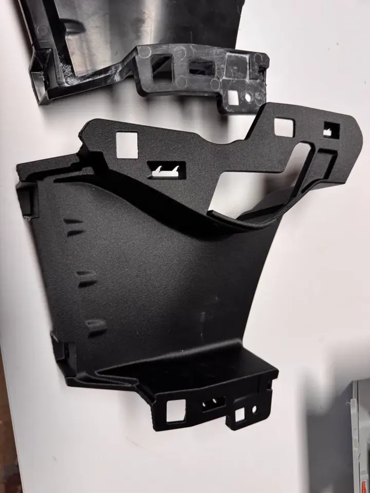 Pièce technique noire de forme complexe refaite sur mesure en impression 3D, avec ses pattes de fixation